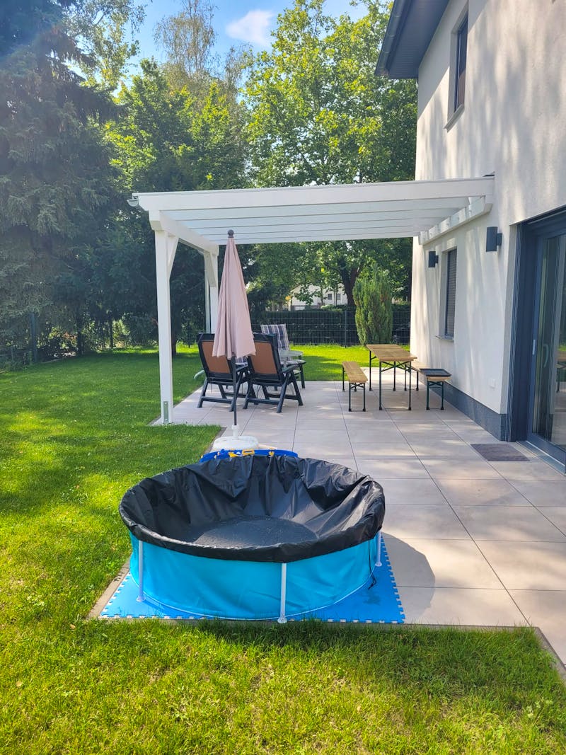 Terrasse und Garten im Sommer 2024 mit Überdachung, Rasen und Planschbecken