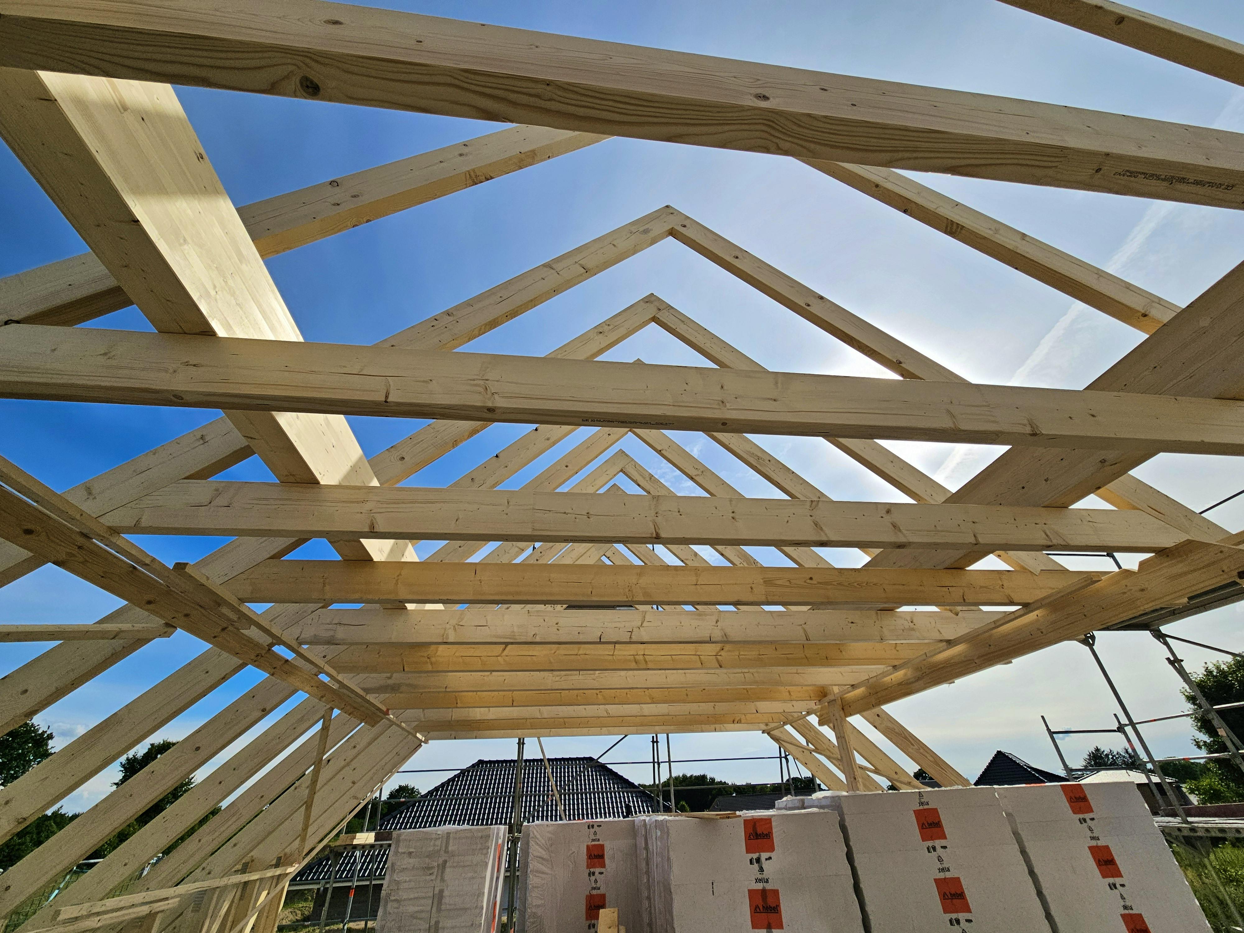 Dachstuhl des Kapitänshauses von innen, frische Holzbalken und Sparren gegen blauen Himmel