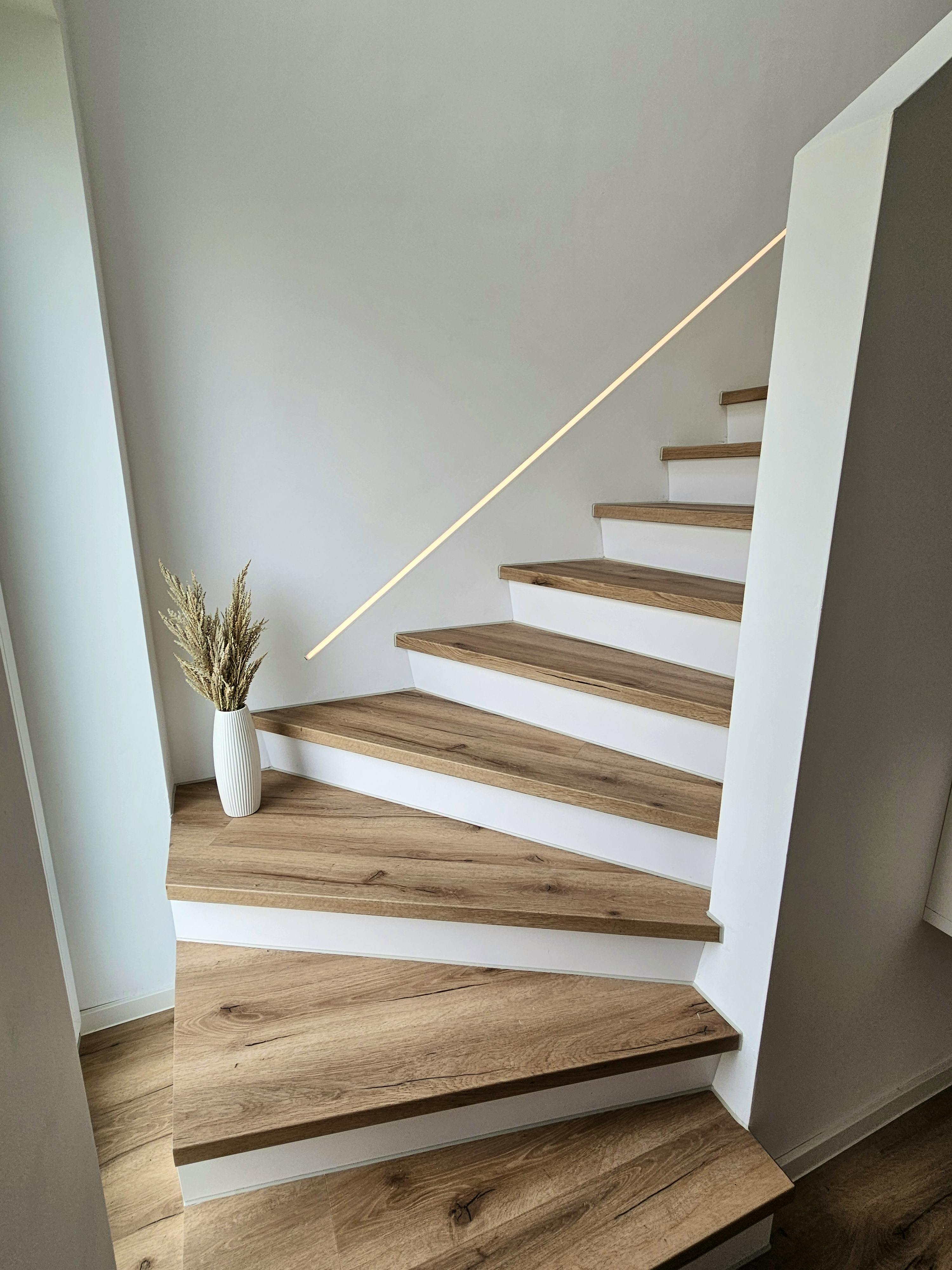 Fertige Treppe mit Eichenstufen, weißen Setzstufen und LED-Handlauf im Kapitänshaus