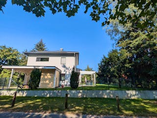 Fertige Stadtvilla bei Berlin mit Carport, Terrassenüberdachung und gepflegtem Garten im Sommer – Bauerfahrung Massivhaus Berliner Umland