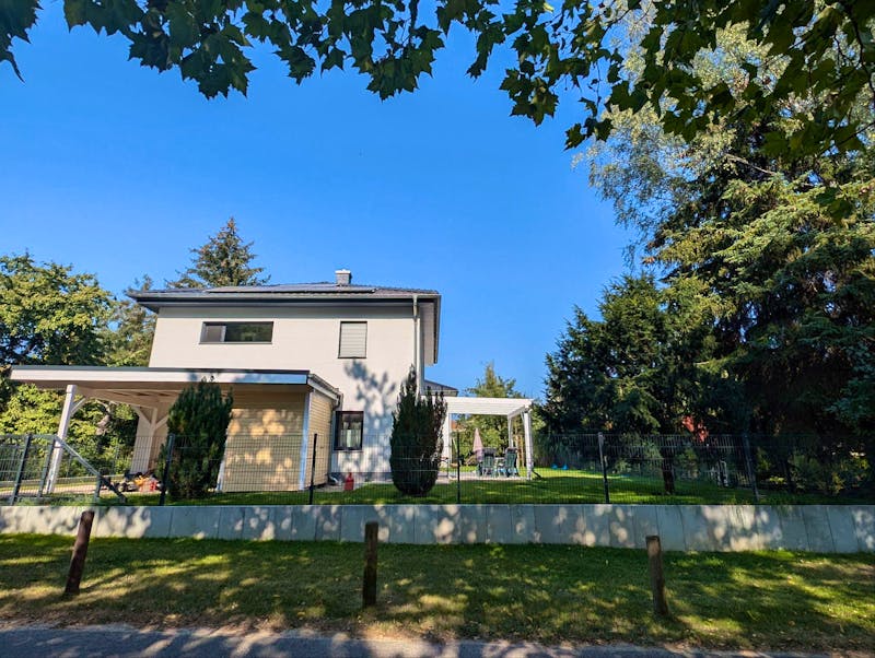 Fertige Stadtvilla in Neuenhagen bei Berlin mit Carport, Terrassenüberdachung und gepflegtem Garten im Sommer – Bauerfahrung Massivhaus Berliner Umland