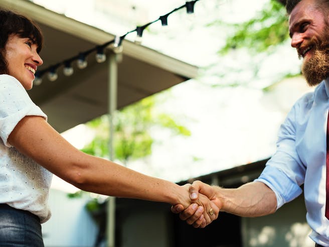 Zwei Menschen gehen einen Deal ein und geben sich freudig die Hand