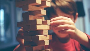 Junge baut Turm aus Holzbausteinen Jenga