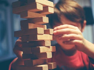 Junge baut Turm aus Holzbausteinen Jenga
