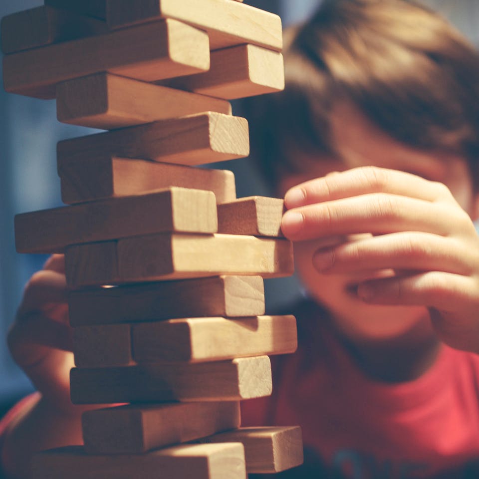 Junge baut Turm aus Holzbausteinen Jenga