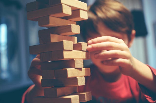 Junge baut Turm aus Holzbausteinen Jenga