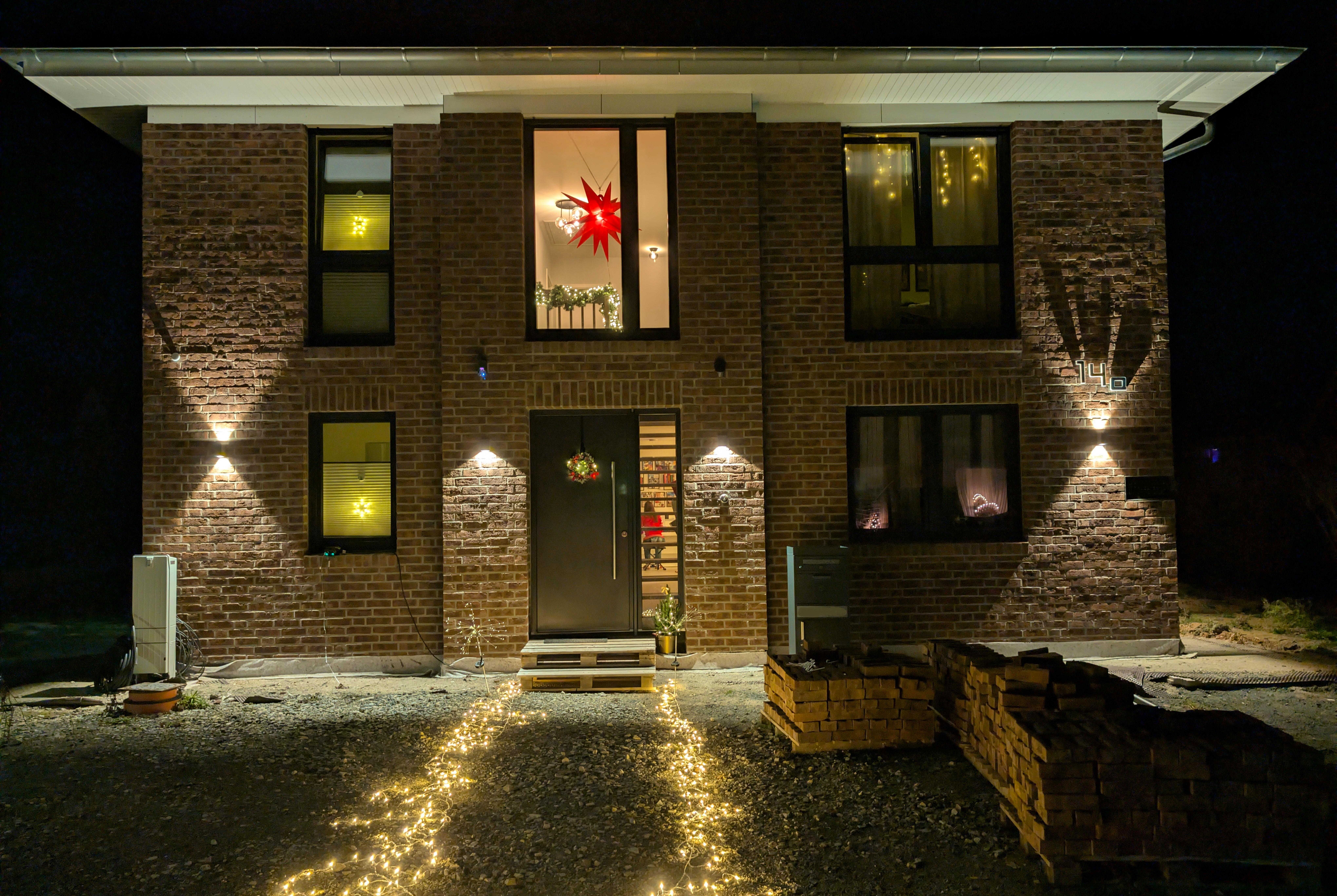 Frontansicht der Viebrockhaus-Stadtvilla in Bodenfelde bei Nacht mit Weihnachtsbeleuchtung – Herrnhuter Stern im Galeriefenster, Lichterkette zum Eingang,