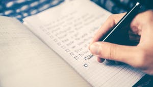 Person schreibt eine Checkliste im Notizbuch