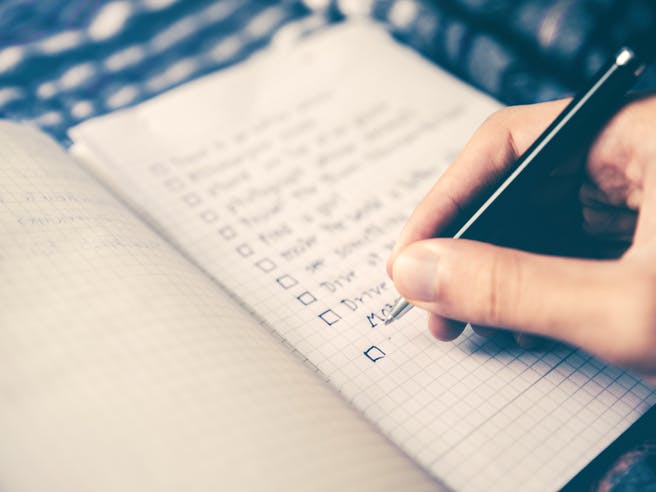 Person schreibt eine Checkliste im Notizbuch