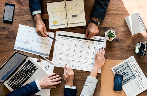 Drei Menschen planen Hausbau am Schreibtisch mit Kalender
