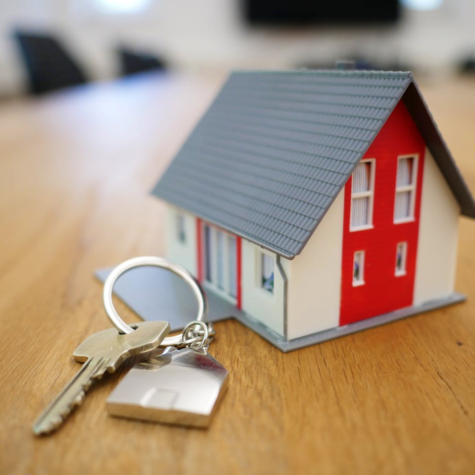 Hausschlüssel vor Miniaturhaus