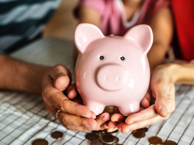 Bauherrenfamilie hält ein Sparschwein in der Hand