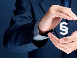 Paragraphenzeichen schwebt zwischen den Händen eines Mannes