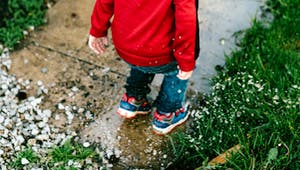 Kind springt in eine Pfütze auf dem Grundstück