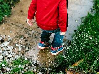 Kind springt in eine Pfütze auf dem Grundstück