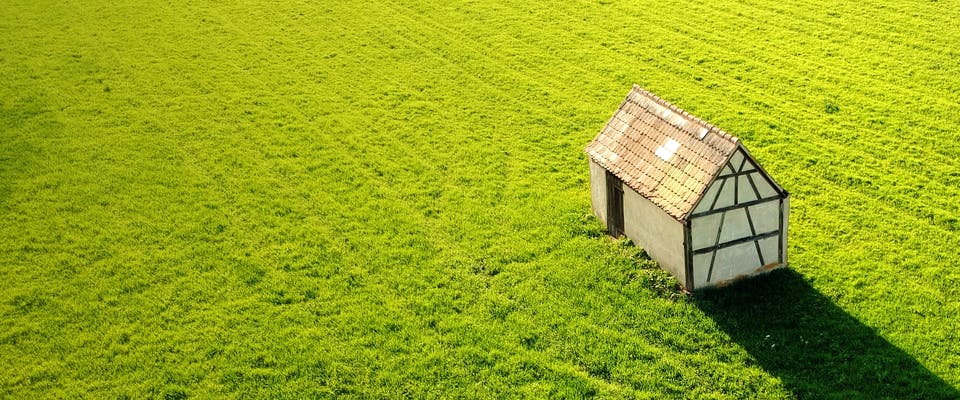 Holzhaus steht allein auf einer weiten Wiese