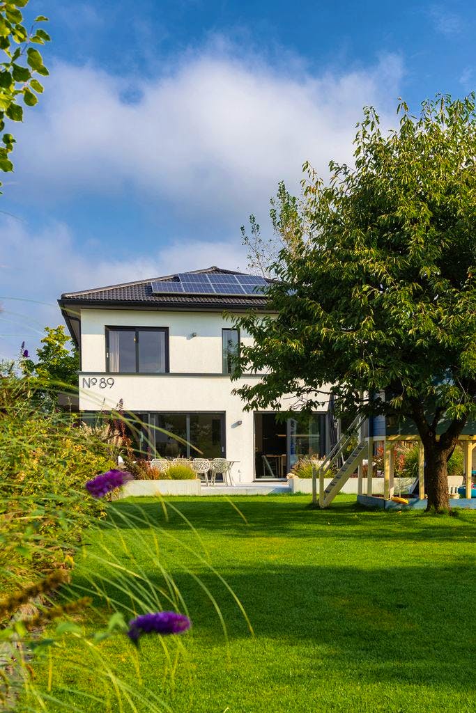 Plusenergie-Fertighaus mit PV-Anlage auf dem Schrägdach und Garten in Berlin