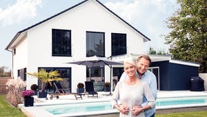 Ehepaar steht vor ihrem neugebautem Haus
