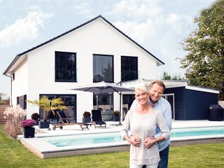 Ehepaar steht vor ihrem neugebautem Haus