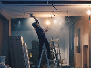 Heimwerker auf Leiter im Holzhaus