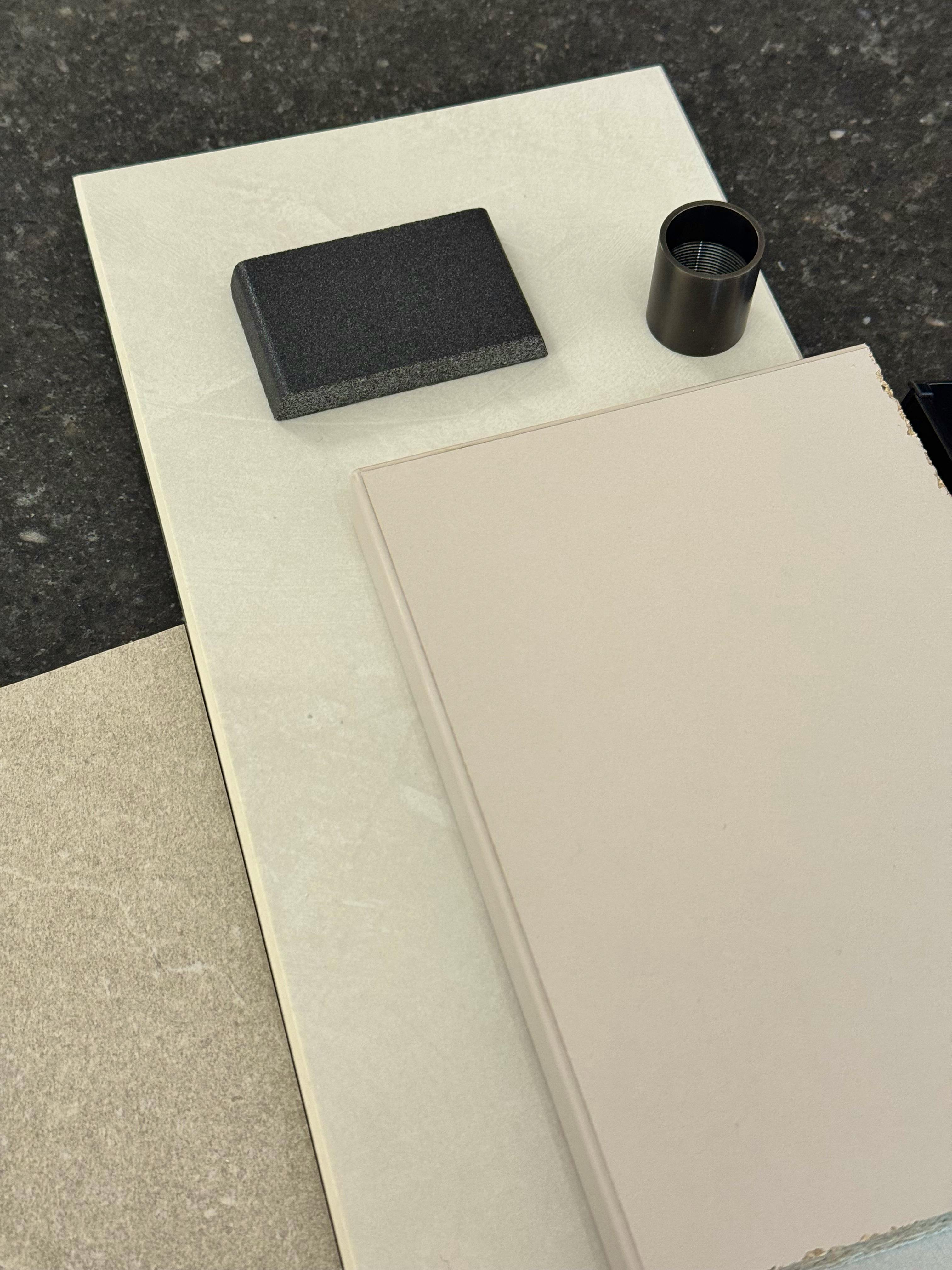 Materialproben für die Bemusterung: Fliese, Arbeitsplatte, Küchenfront und dunkle Armatur nebeneinander