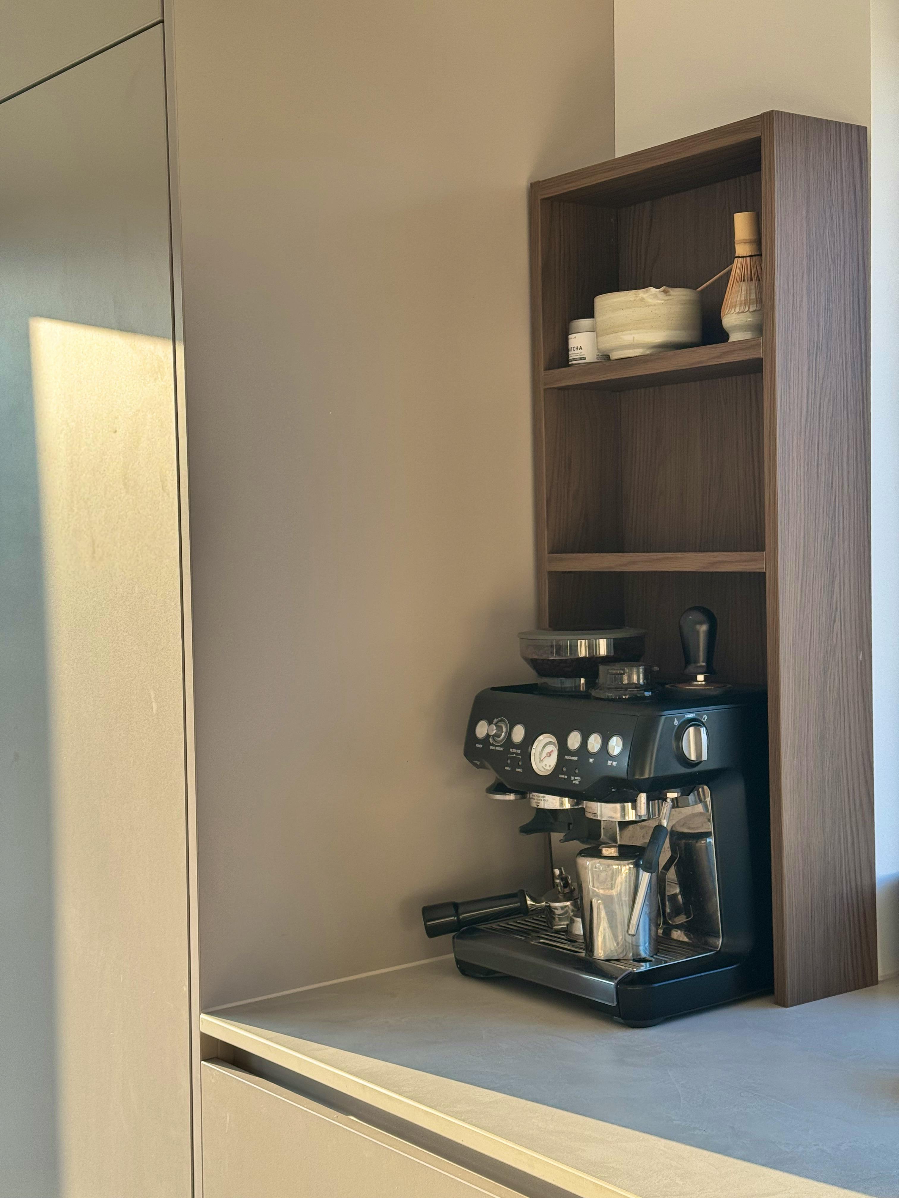 Siebträger-Kaffeemaschine in einem offenen Holzregal neben beigefarbener Küchenfront