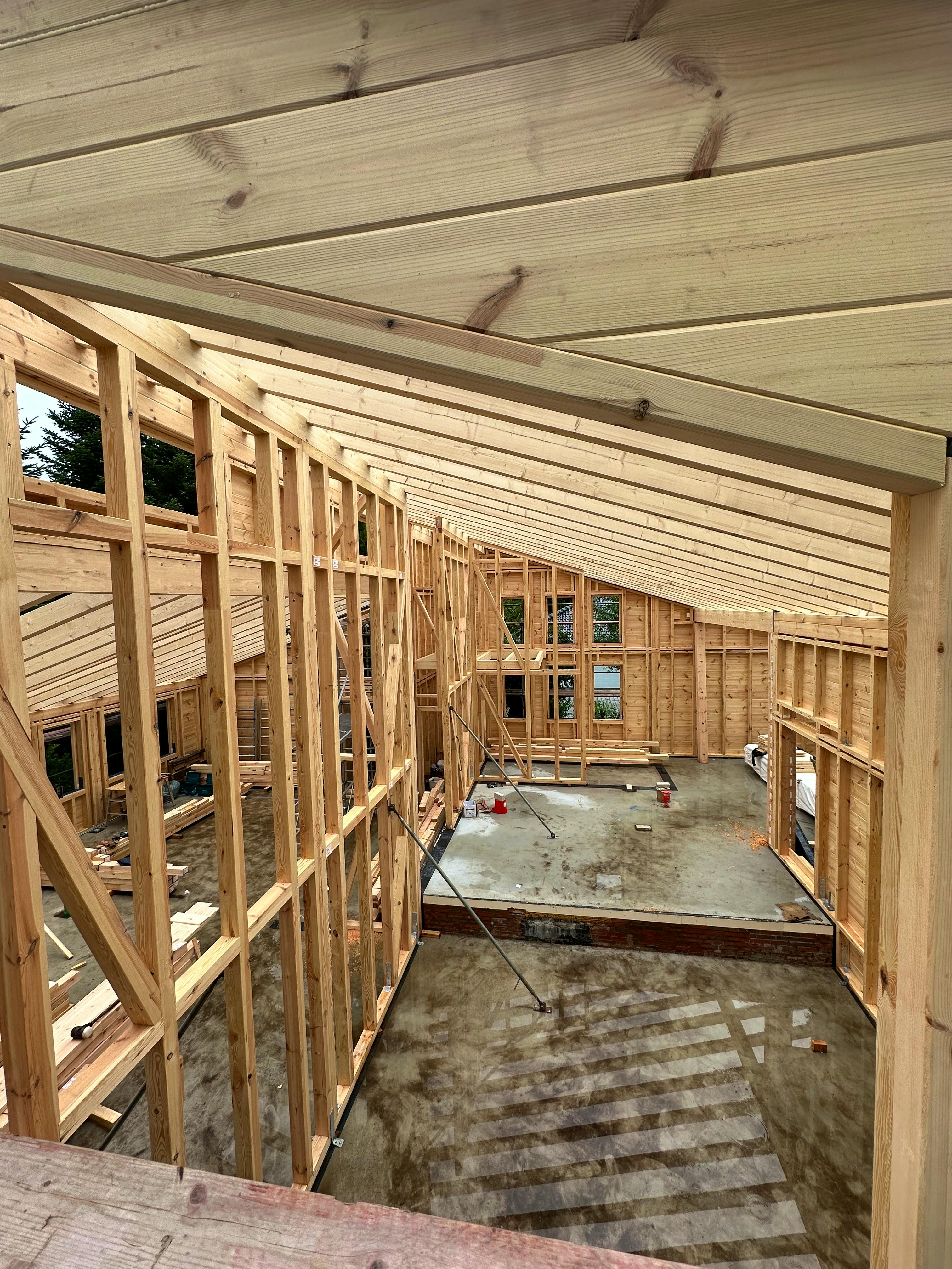 Rohbau-Innenansicht des Fullwood-Blockhauses mit sichtbarem Holzständerwerk, Pultdach-Konstruktion und Höhenversatz zwischen den Ebenen