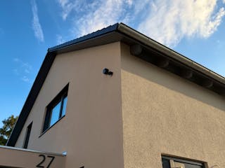 Außenansicht des LUXHAUS-Fertighauses mit Satteldach, beigefarbener Fassade und Doppelgarage