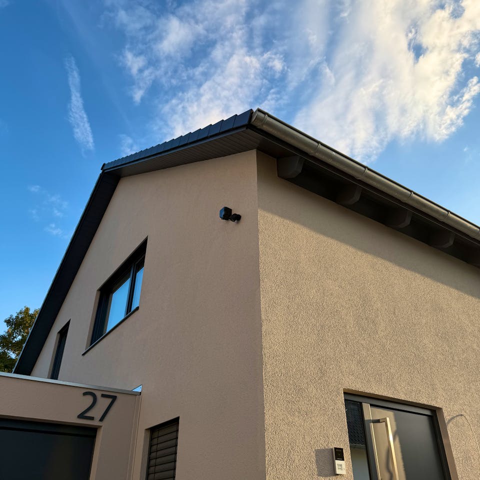 Außenansicht des LUXHAUS-Fertighauses mit Satteldach, beigefarbener Fassade und Doppelgarage