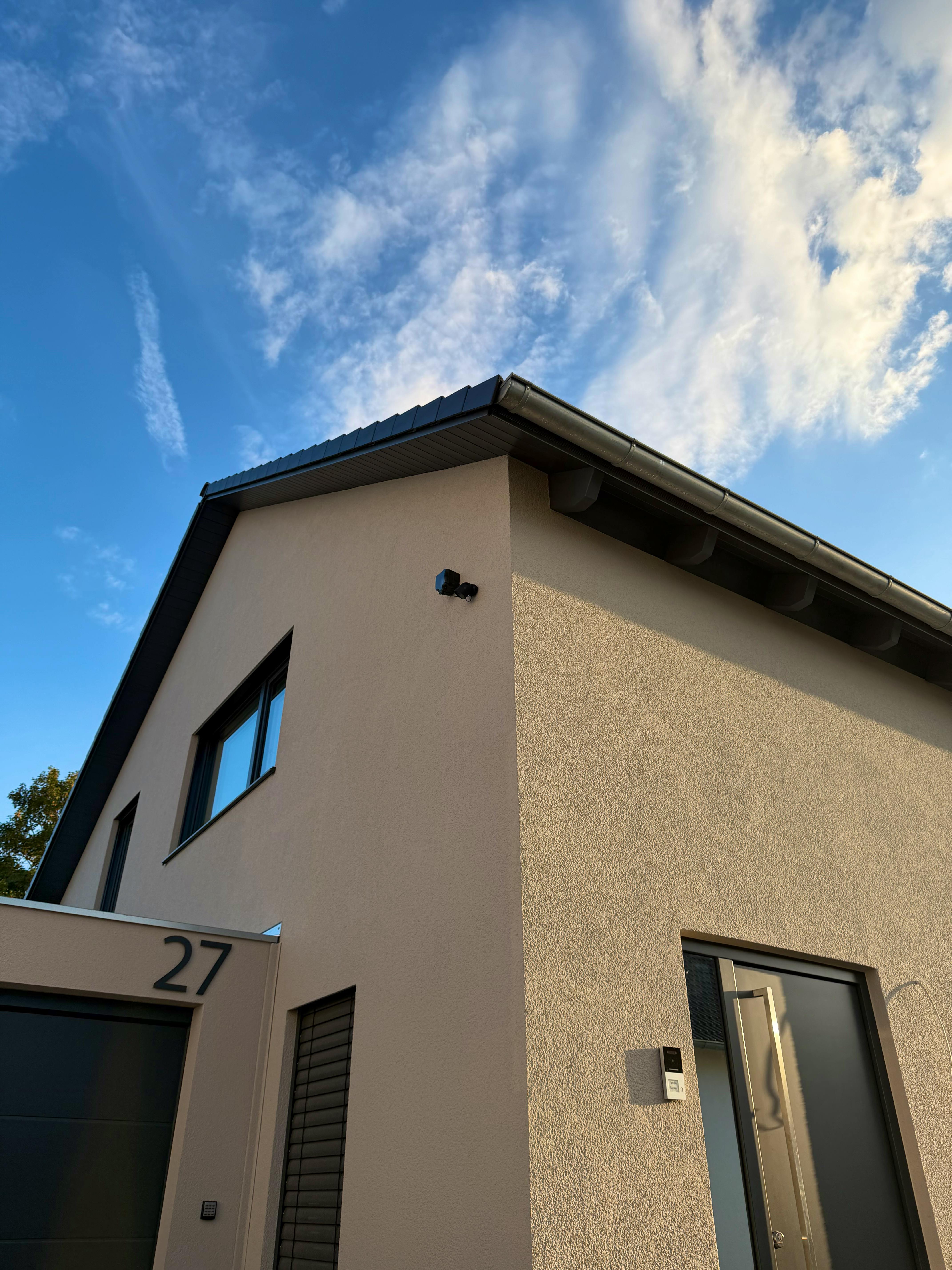 Außenansicht des LUXHAUS-Fertighauses mit Satteldach, beigefarbener Fassade und Doppelgarage