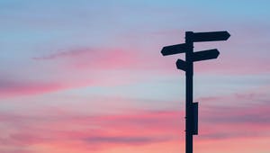 Wegweiser zeigt in verschiedene Richtungen bei Sonnenuntergang