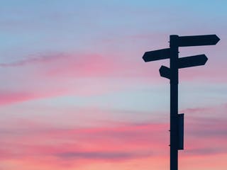 Wegweiser zeigt in verschiedene Richtungen bei Sonnenuntergang