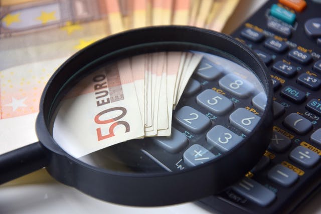 Geld mit Lupe und Rechner