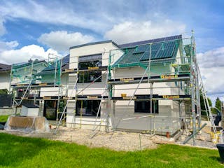 Neubau eines modernen Einfamilienhauses mit Gerüst und Solaranlage auf dem Dach – ein konkretes Bauprojekt einer Baufamilie auf Fertighaus.de