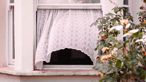 Offenes Fenster aus dem eine weiße Gardine rausweht