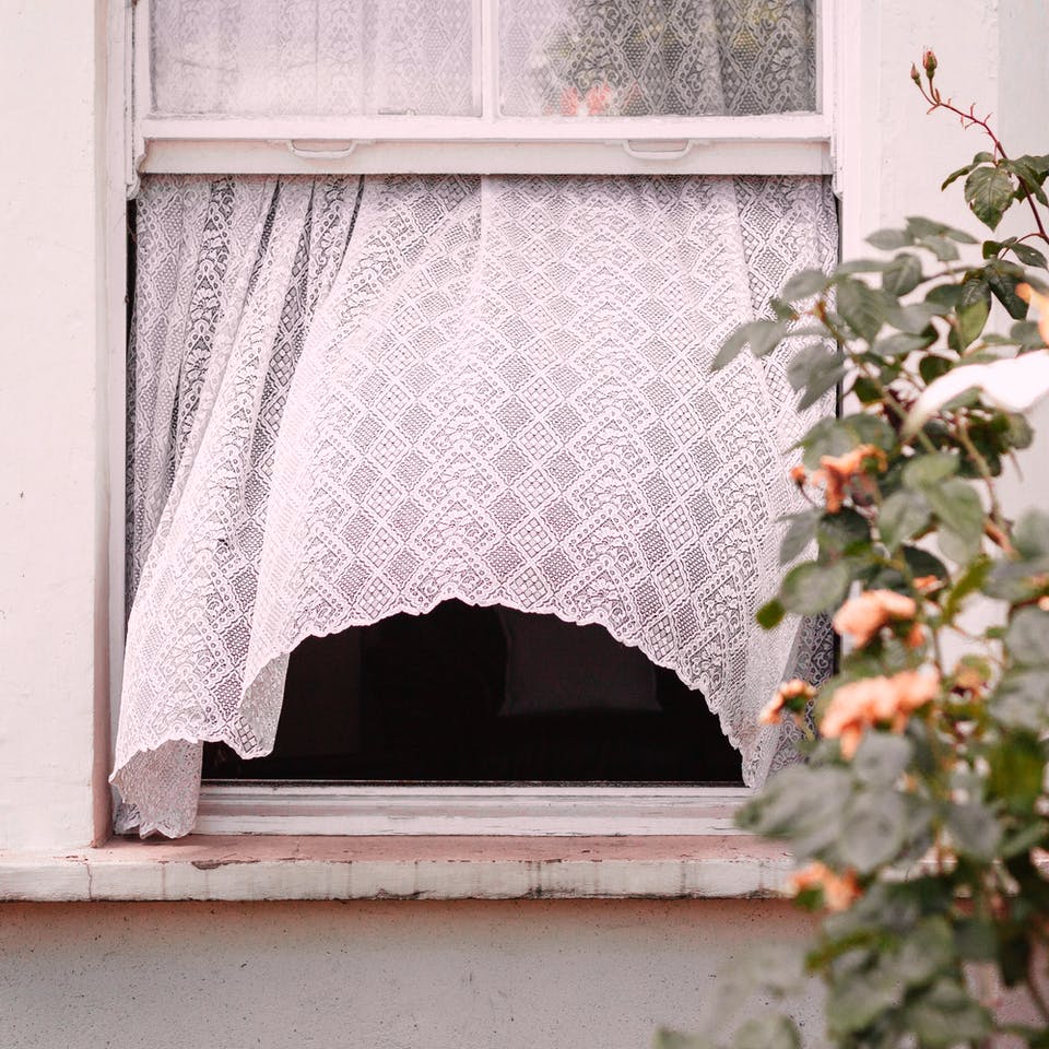 Offenes Fenster aus dem eine weiße Gardine rausweht