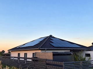 Bungalow mit Walmdach und Photovoltaik-Anlage in der Abenddämmerung