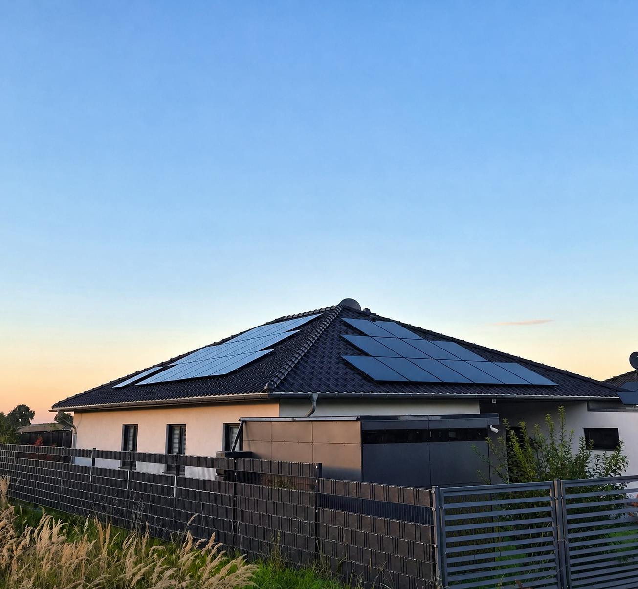 Bungalow mit Walmdach und Photovoltaik-Anlage in der Abenddämmerung