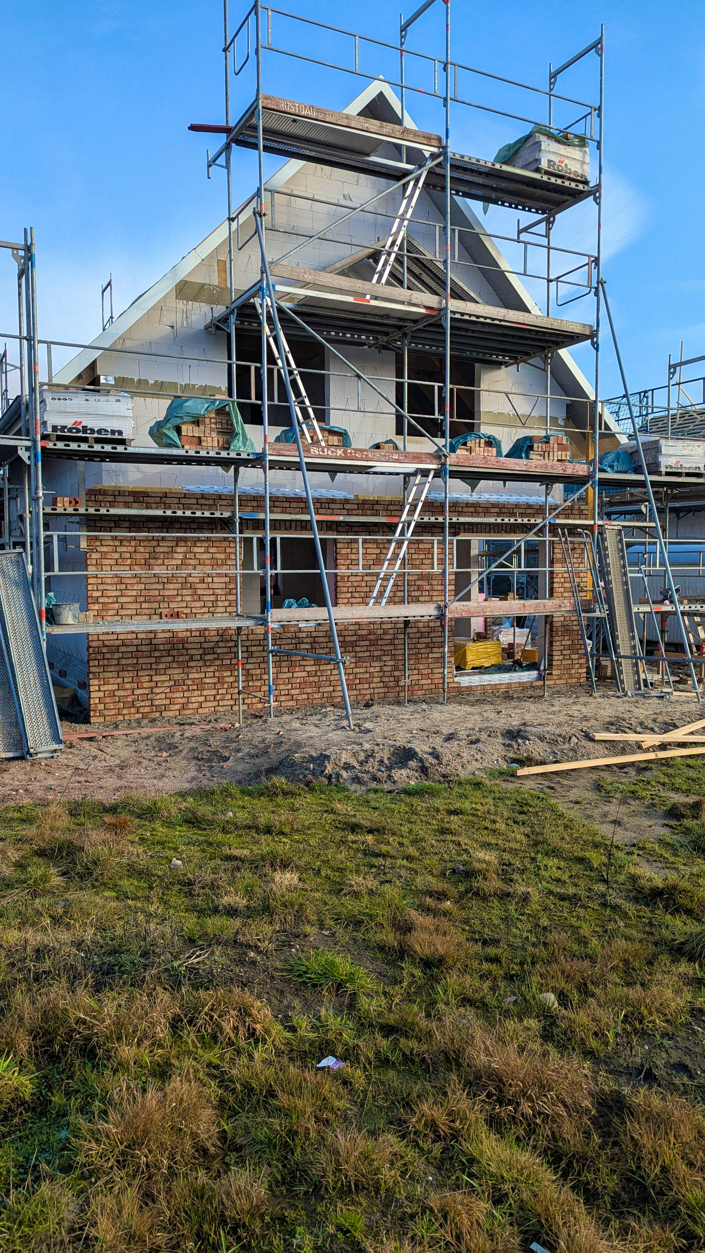 Verklinkerung der Fassade in Arbeit, untere Reihen aus hellem Klinker gemauert, Giebelbereich noch Porenbeton