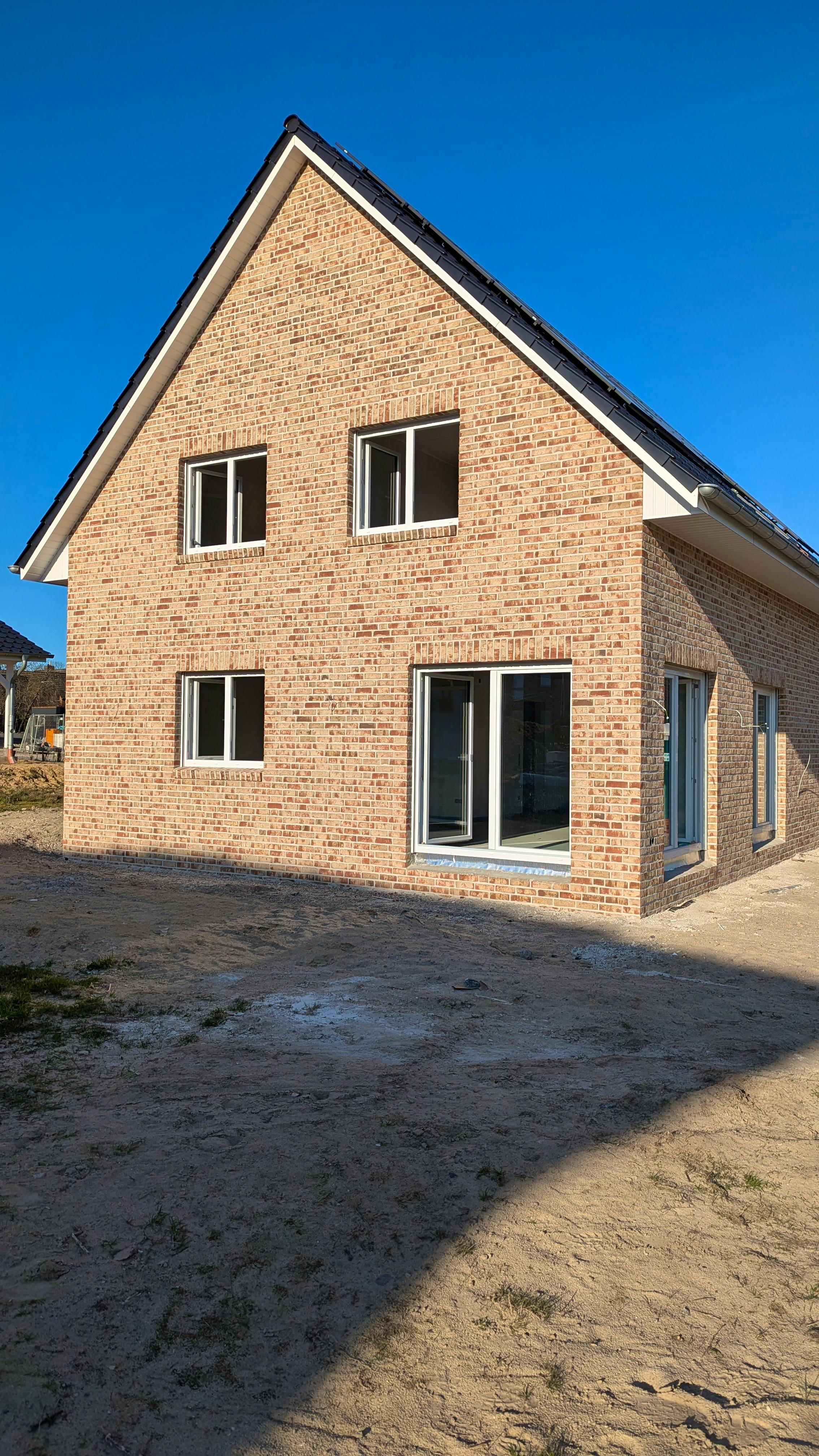 Fertiges verklinkertes Einfamilienhaus mit Satteldach, davor unbefestigter Sandboden ohne Terrasse
