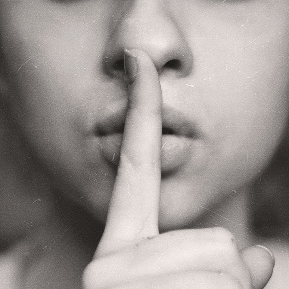 Frau hält Finger vor den Mund um Stille zu fordern
