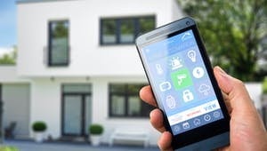 Smarthome App wird vor dem Haus auf dem Smartphone bedient