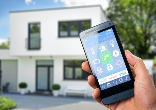 Smarthome App wird vor dem Haus auf dem Smartphone bedient