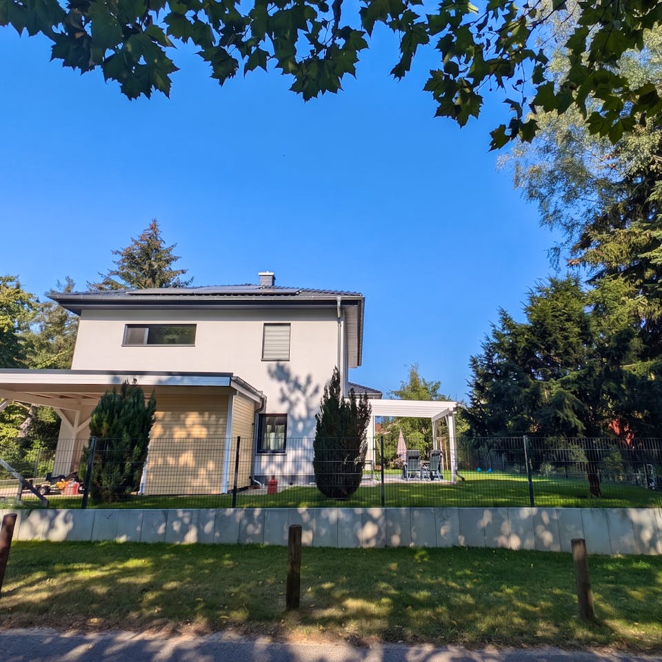 Fertige Stadtvilla bei Berlin mit Carport, Terrassenüberdachung und gepflegtem Garten im Sommer – Bauerfahrung Massivhaus Berliner Umland