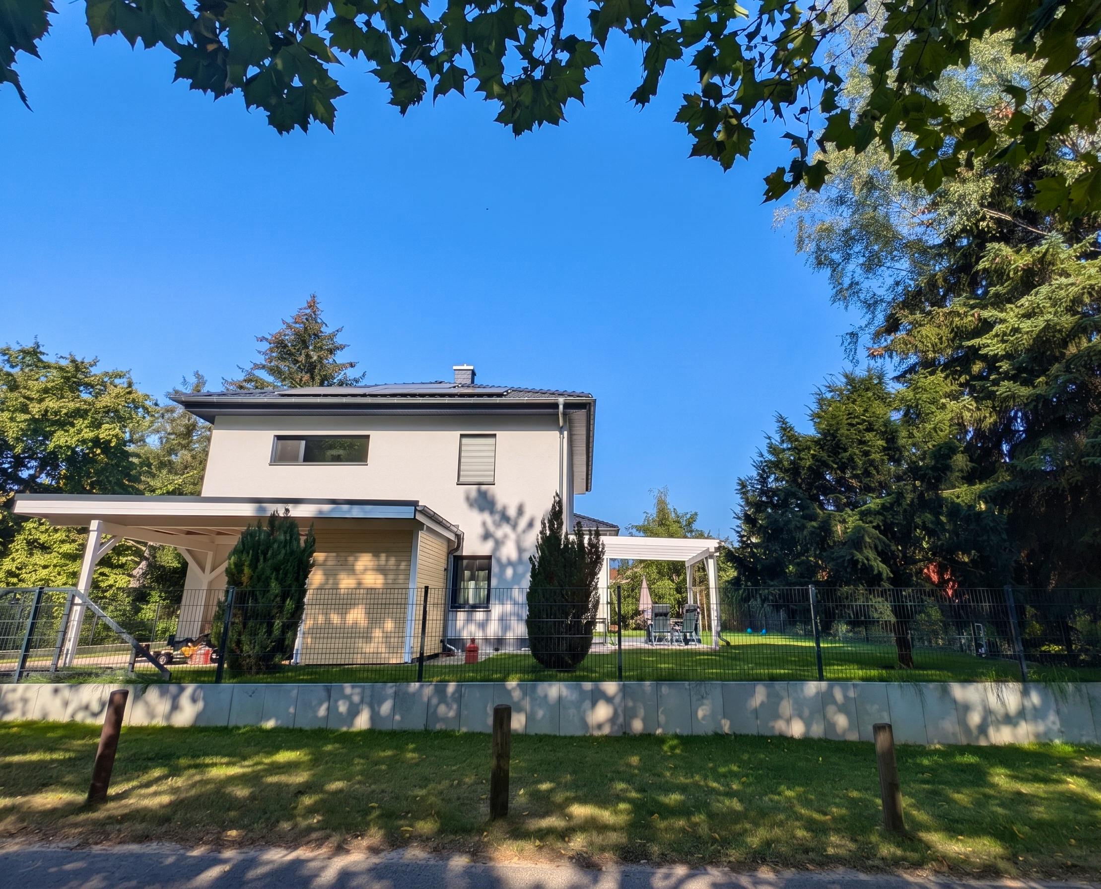Fertige Stadtvilla bei Berlin mit Carport, Terrassenüberdachung und gepflegtem Garten im Sommer – Bauerfahrung Massivhaus Berliner Umland