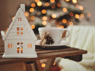 Weißes Teelichthaus vor Weihnachtsbaum