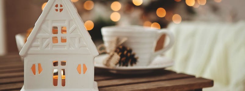 Weißes Teelichthaus vor Weihnachtsbaum
