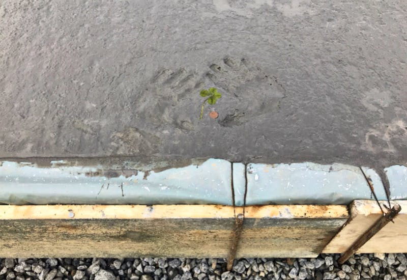 Handabdrücke, Kleeblatt und Centstück im weichen Beton der Bodenplatte beim Haus
