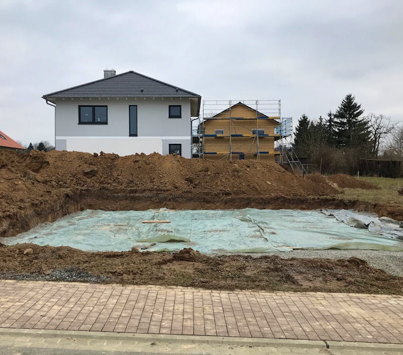 Ausgehobene Baugrube für Hausbau mit Plane bedeckt