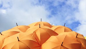 Viele orangenfarbene Sonnenschirme unter blauem Himmel